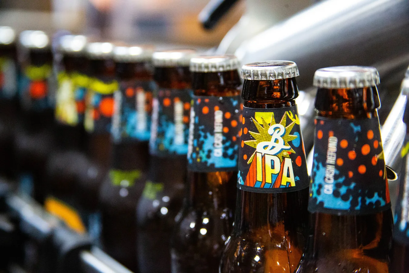 Close-up row of Brooklyn beer bottles with comic-style blue and orange labels, one reading IPA in a starburst