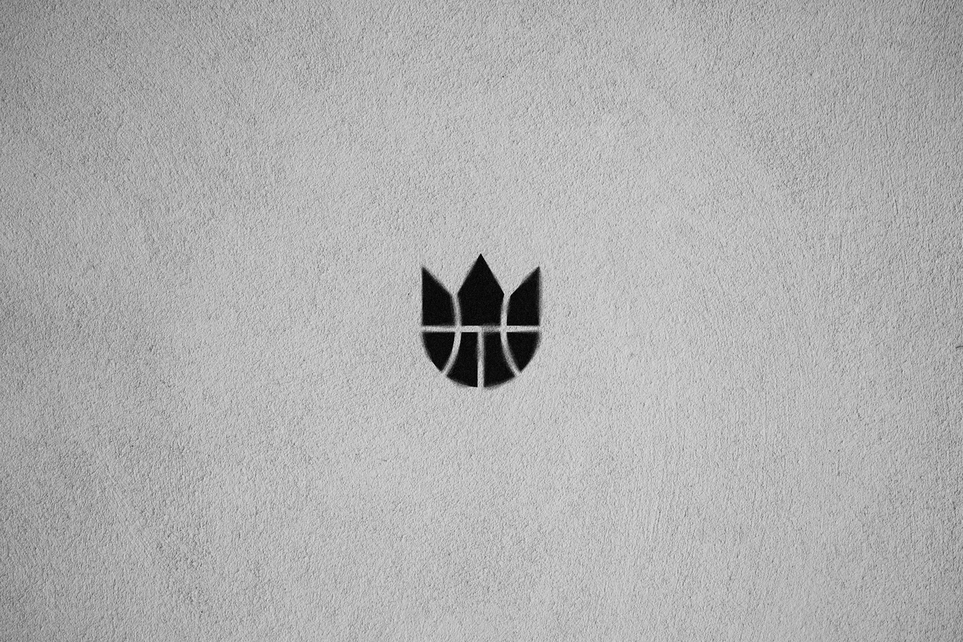 Black Kings crown-and-basketball brandmark centred on a textured light grey wall