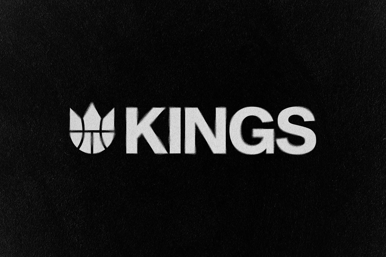 White KINGS wordmark with the crown-and-basketball mark on a textured black background