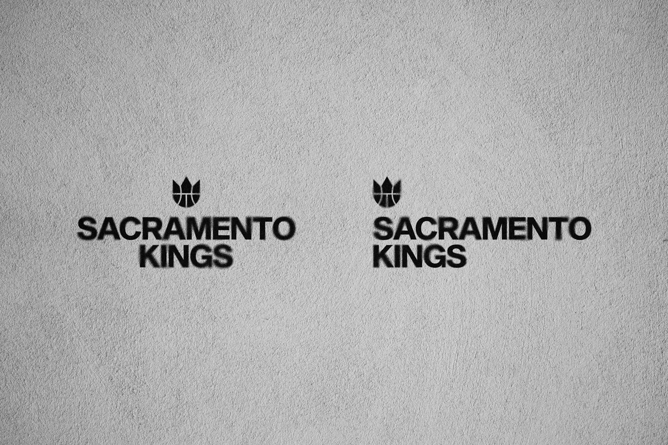 Two stacked SACRAMENTO KINGS lockups in black type with a small crown mark above each, on a textured light grey wall