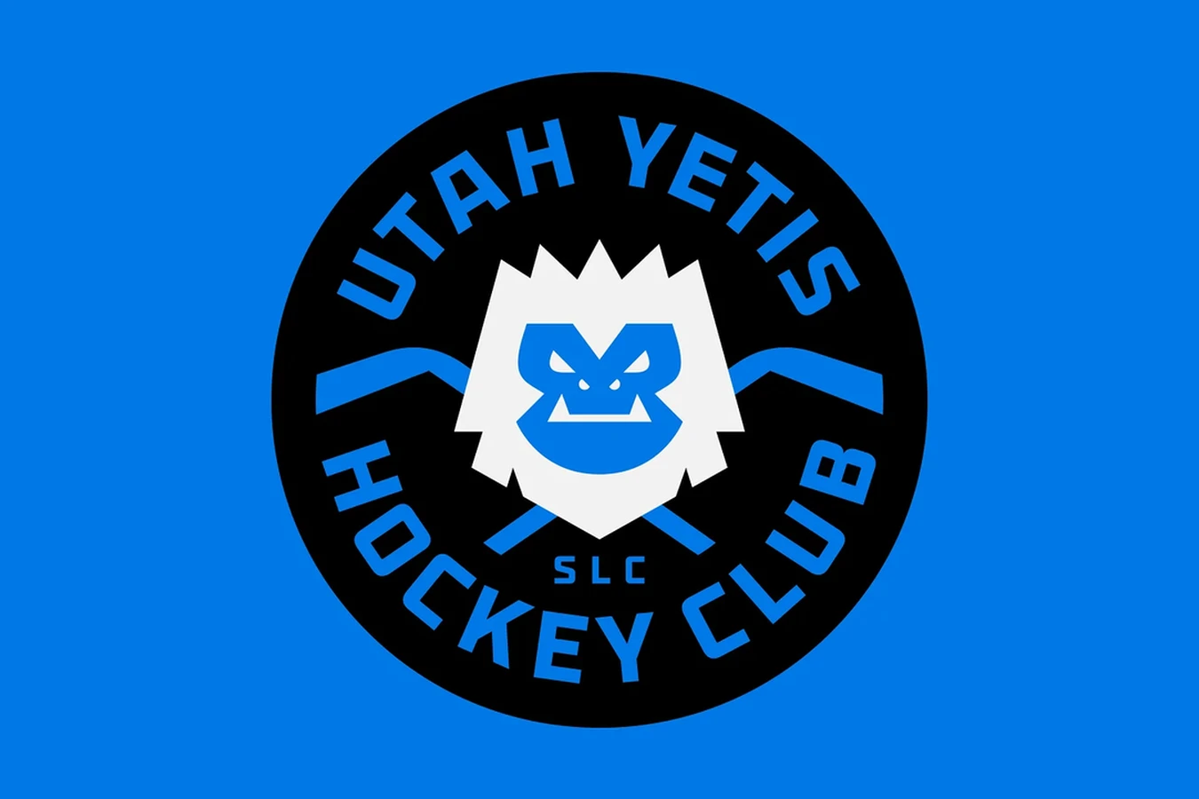 Circular Utah Yetis Hockey Club SLC badge in black and blue, a white yeti face over crossed sticks, on blue